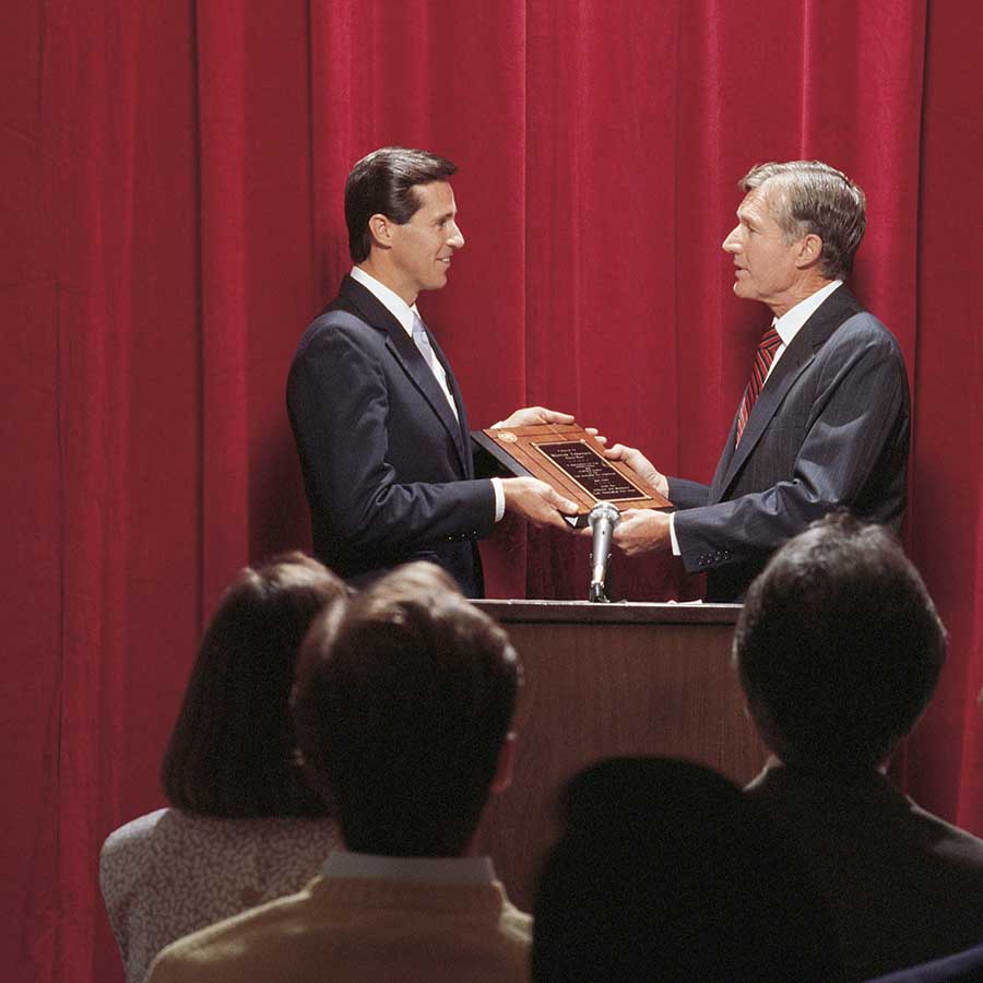 Businessmen accepting award on stage