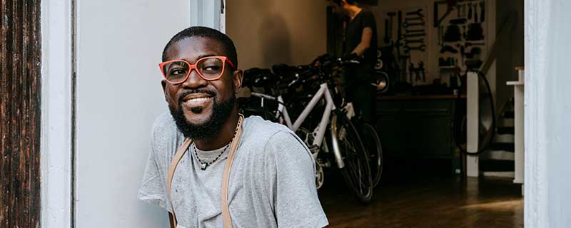 Confident male owner with funky eyeglasses looking away outside bicycle shop